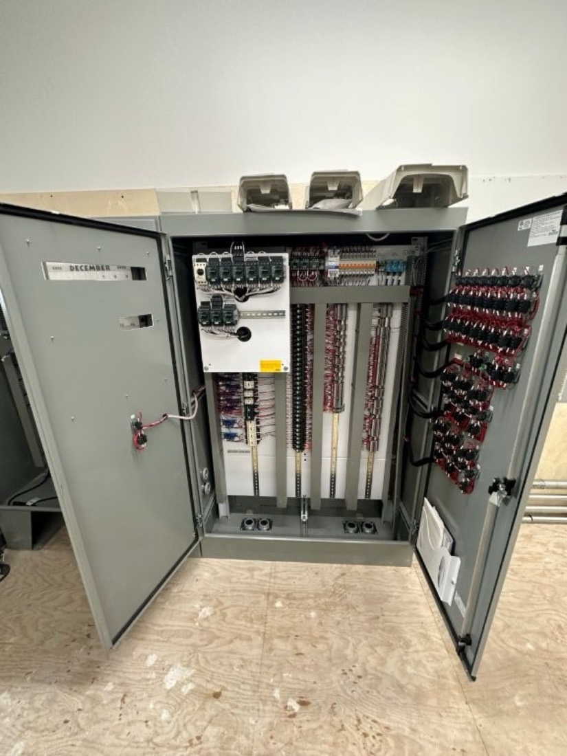 The inside of an industrial control panel showing organized wiring, terminal blocks, and relays.