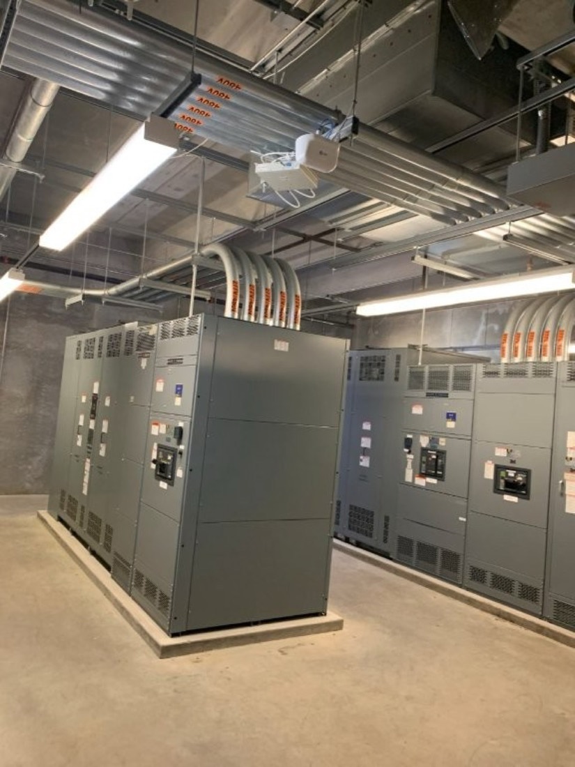 A lineup of gray electrical switchgear sections installed inside a commercial building.